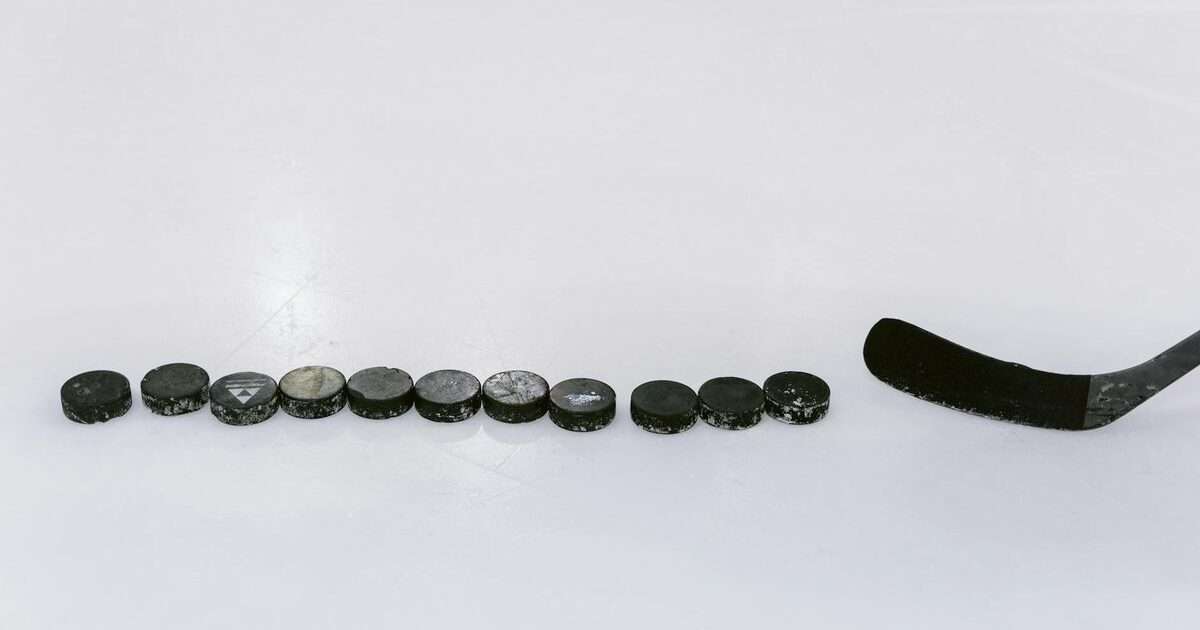 hokej online: A row of hockey pucks and a stick on an ice rink, perfect