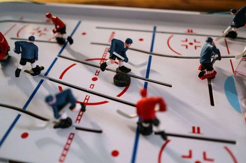 hokej online: Closeup on a table hockey game showcasing figurines in motion on the playing