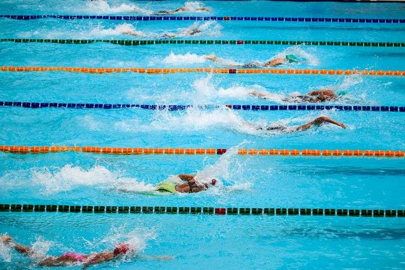 jilek olympiada program: Swimmers compete in an outdoor pool race, showcasing athleticism and sportsmanship