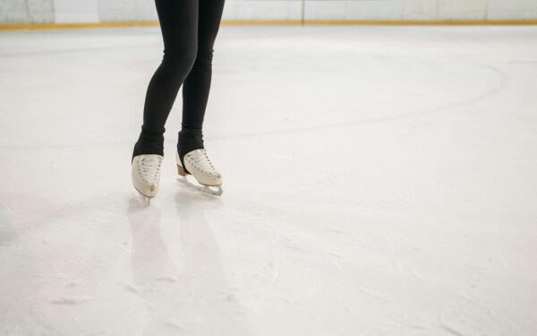 kaori sakamoto: Close-up of a figure skater's legs and skates gliding on an ice rink